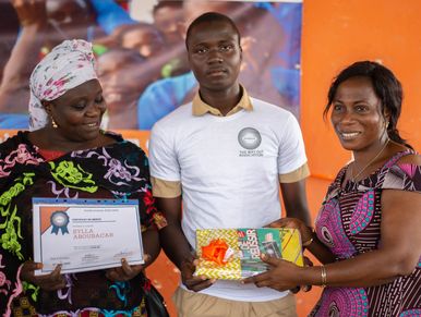 Three people at an award ceremony with a certificate and gift exchange.